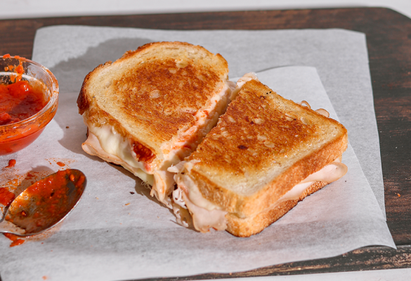 Chicken parm grilled cheese sandwich on a chopping board